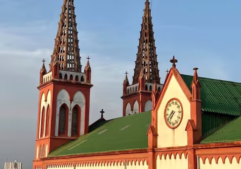 A red church with twin towers and a green roof